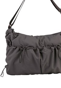 Gray nylon shoulder bag with adjustable strap, gathered design, elastic drawstrings, and zipper detailing, featuring smooth texture and soft fabric.
