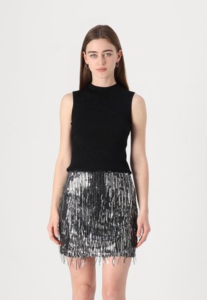Black ribbed sleeveless top paired with a silver sequin miniskirt featuring vertical fringe details, creating a textured, reflective look.
