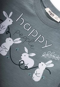 Sivá mikina s bielymi ilustráciami zajačikov a textom "šťastní ľudia." Zaujímavé detaily zahŕňajú modré akcenty a kučeravé línie.