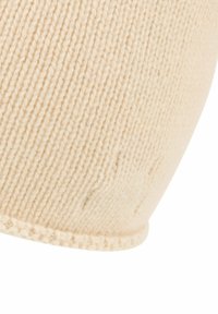 Knit cream-colored beanie with a ribbed texture and a curved hem, featuring a smooth finish and subtle stitching details.
