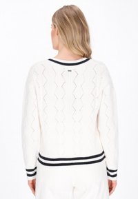 Maglione bianco lavorato a maglia con un motivo testurizzato, orlo e polsini a righe nere, caratterizzato da un dettaglio a scollatura a V sul retro.