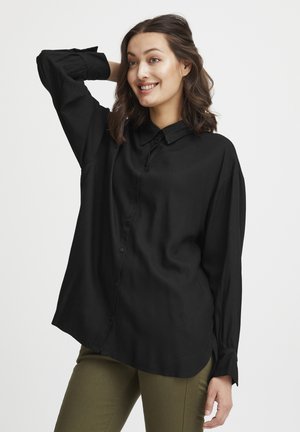 Black button-up shirt with a collar, long sleeves, and a relaxed fit. The fabric appears smooth with a subtle sheen. Worn with olive green pants.