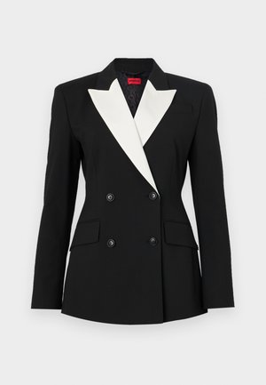 Blazer preto com frente de dupla abotoadura, lapela xale branca, dois bolsos frontais e botões pretos. Feito de tecido estruturado.