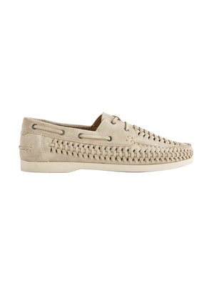 Beige suede loafer with woven detailing along sides and top, lace eyelets, and a flat rubber sole.