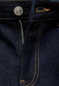 Jeans de mezclilla azul oscuro con un botón de metal, cierre de cremallera y costuras amarillas en contraste. Presenta un diseño clásico de cinco bolsillos y una textura de tela duradera.