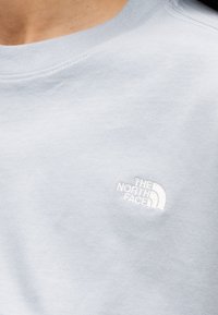 Ανοιχτό μπλε φούτερ με ριμπ γιακά, βαμβακερό υλικό, με λευκό κεντητό λογότυπο The North Face στο στήθος.