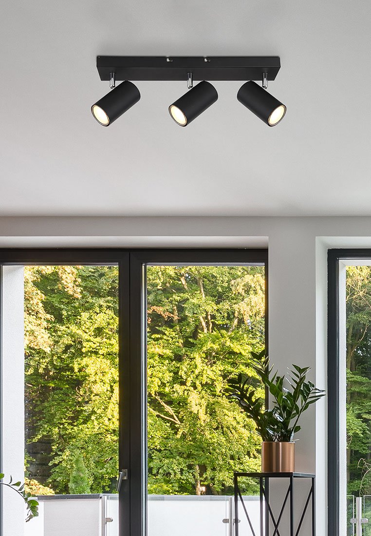 Schwarze Metall-Deckenleuchte mit drei zylindrischen Schirmen, von denen jeder eine Glühbirne beherbergt. An einer horizontalen Stange montiert.