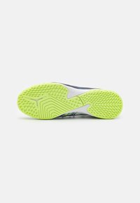Suola della scarpa con un motivo testurizzato, prevalentemente giallo-verde e bianco, caratterizzata da scanalature e punte per la trazione. La parte superiore è grigia e blu.