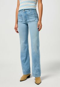 Jeans de ganga azul claro com um design de perna reta. As características incluem cinco bolsos, fecho de botão e detalhes de costura discretos.