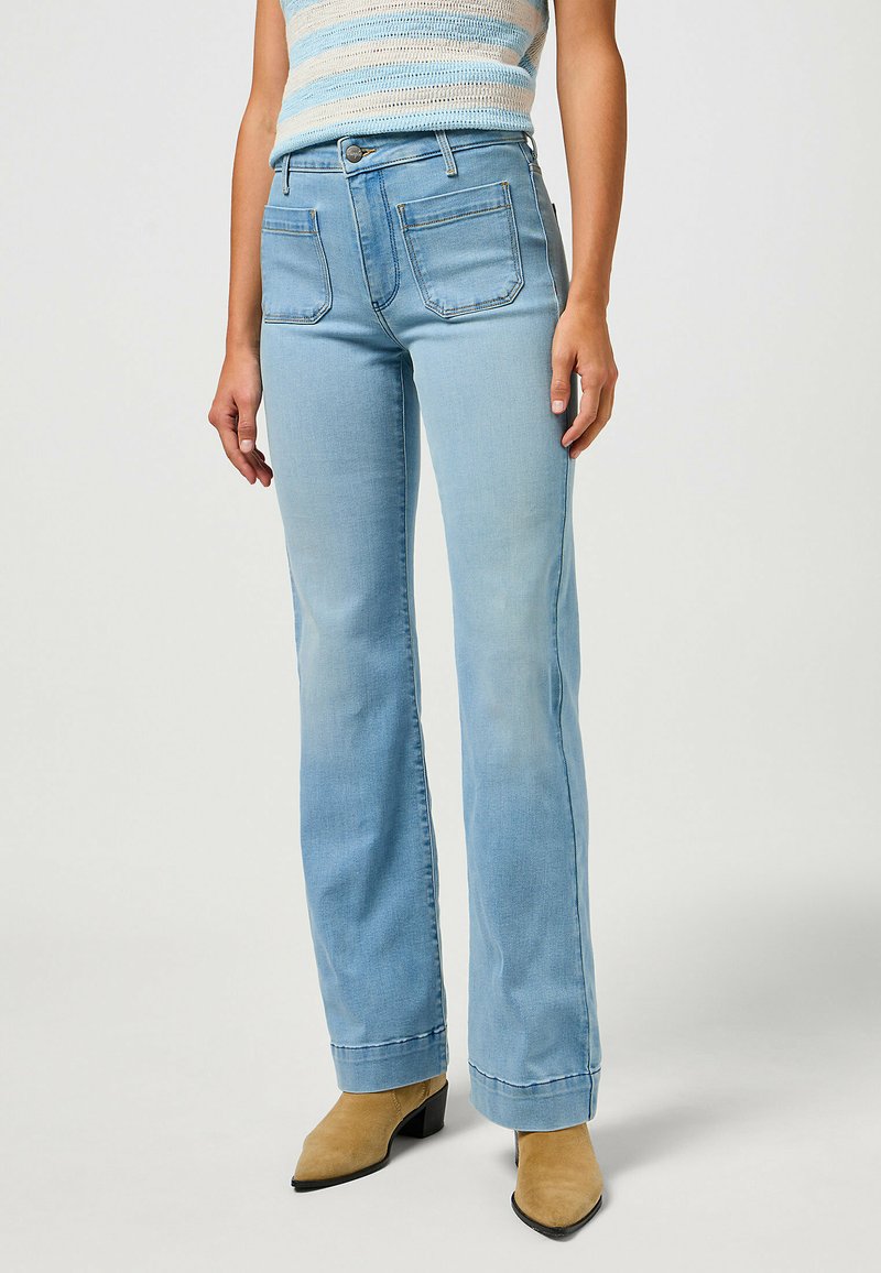 Jeans de ganga azul claro com um design de perna reta. As características incluem cinco bolsos, fecho de botão e detalhes de costura discretos.