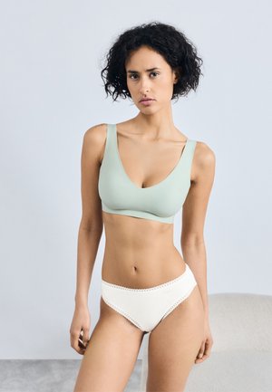 Soutien-gorge vert clair avec un décolleté en V profond et des bretelles épaisses, associé à des culottes blanches avec une bordure en dentelle le long de la taille.