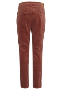 Un pantalon en velours côtelé couleur orange brûlé, avec une texture lisse, une coupe droite, deux poches arrière et une étiquette en cuir au niveau de la taille.