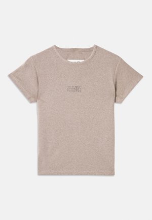 Henkilö, jolla on beige t-paita, mustat nahkahousut, harmaa neulepusero vyötäröllä sidottuna, mustat loafers-kengät ja pidellen pientä vaaleanpunaista käsilaukkua.