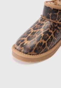 Čizme s leopard uzorkom s sjajnom završnom obradom, mekim krznom unutrašnjosti, te smeškim gumenim đonom s teksturiranim akcentima i šivenim detaljima.