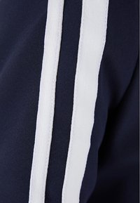 Marinäverkat tyg med två vertikala vita ränder. Materialet ser slätt ut med en lätt glans och ger ett strukturerat utseende.