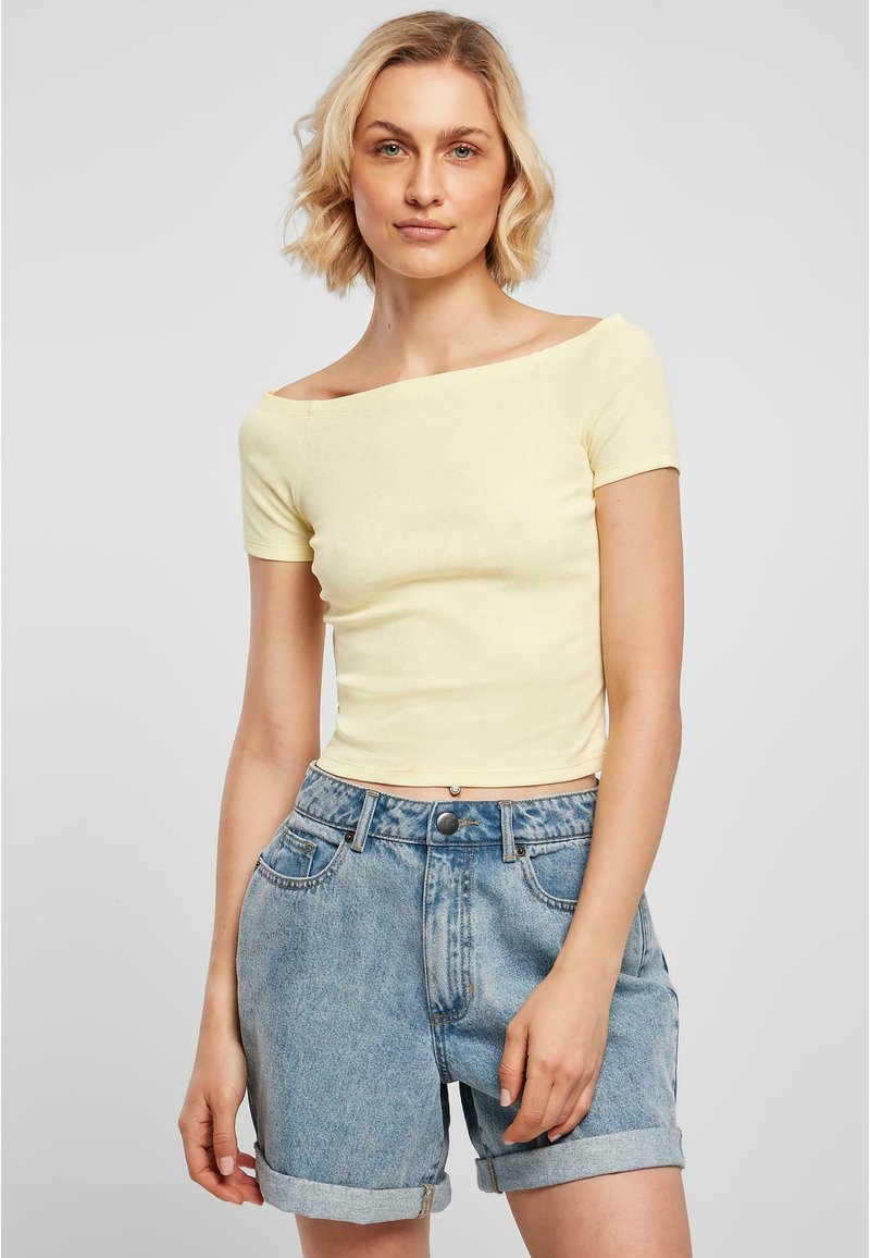Gul ribbad off-shoulder topp med korta ärmar, parat med högmidjade, uppvikta blå denimshorts. Slät textur, avslappnad design.