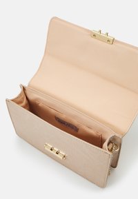 Clutch in materiale testurizzato beige chiaro, con chiusura in tono oro, dotato di un interno simile al velluto e di un'etichetta all'interno.