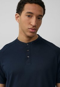 Marineblauwe short-sleeve shirt met een ronde kraag en een placket met drie knoppen. Zachte stof met een gladde textuur en een minimalistisch ontwerp.