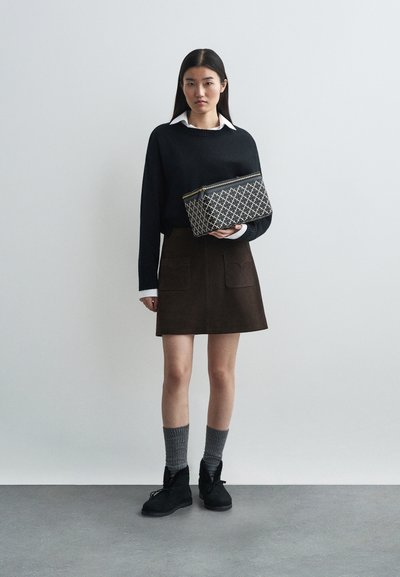 Svart tröja med vit krage, brun mockaskirt med fickor, mönstrad svart och vit väska, grå strumpor, svarta ankelstövlar.