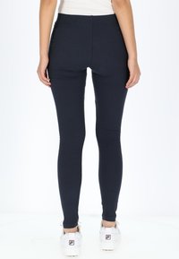 Marineblauwe geribde leggings met een hoge tailleband, een getailleerd silhouet en een gladde textuur, gecombineerd met witte sportschoenen.