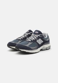 Buty sportowe w kolorystyce granatowo-szarej, wykonane z siateczki i zamszu, z wyściółką przy kołnierzu, sznurówkami oraz wzmocnionym noskiem.