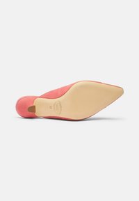 Koraalrode suède puntige pump met een slanke stilettohak en een gladde beige zool met reliëfbranding en een ronde hakkap.