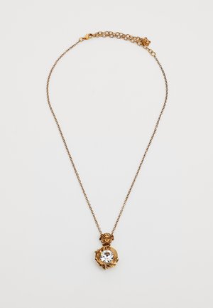 Collier en chaîne en or avec un pendentif en forme de tête de lion tenant une grande pierre précieuse claire entourée de feuilles d'or ornées.