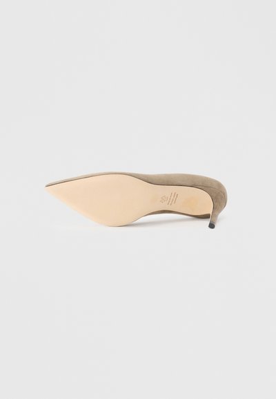 Beige suede stiletto heel shoe with a pointed toe and a smooth, light-colored sole. Subtle branding embossed on the inner sole.