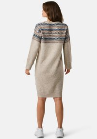 Gebreide jurk in beige met een gemêleerde, kleurrijke yoke. Kenmerken zijn lange mouwen, geribbelde manchetten en zoom. Middenlange stijl, zachte textuur.