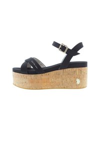 Sandaal negro de tiras con cuña de corcho y hebilla ajustable en el tobillo, que presenta un pequeño emblema dorado en el lado del tacón.