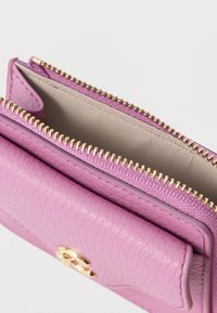 Pink leather wallet with a textured finish and gold zipper. It features an interior pocket, showcasing a simple, clean design.