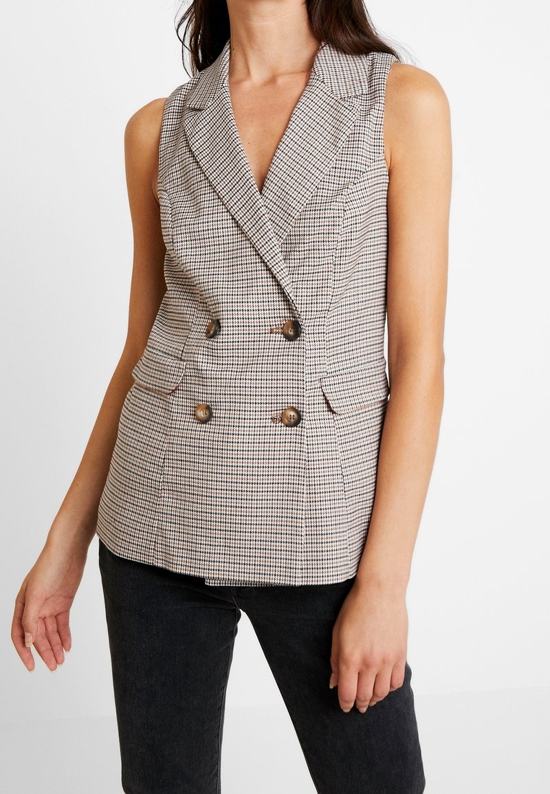 Dubbelt knäppt väst i rutigt mönster; har en slagkrage, två framfickor, guldtonade knappar och en figursydd design.