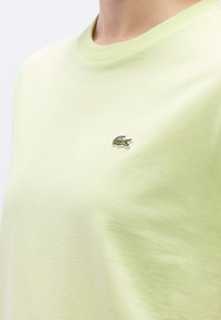 Ανοιχτό πράσινο βαμβακερό t-shirt με στρογγυλή λαιμόκοψη κ�αι μικρό κεντημένο λογότυπο κροκόδειλου στο αριστερό στήθος. Μαλακή υφή, απλός σχεδιασμός.