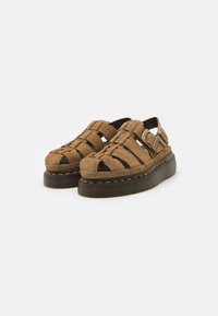 Brune semsket stroppesandaler med åpen tå, tykk plattformsåle og kontrasterende gul søm. Har en justerbar spenne.