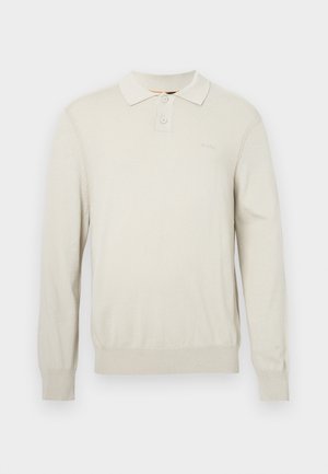 Cremfarbendes langärmliges Polohemd aus weichem Strickstoff. Mit klassischem Kragen, zwei Knöpfen sowie gerippten Bündchen und Saum. Dezentes Logo auf der Brust.