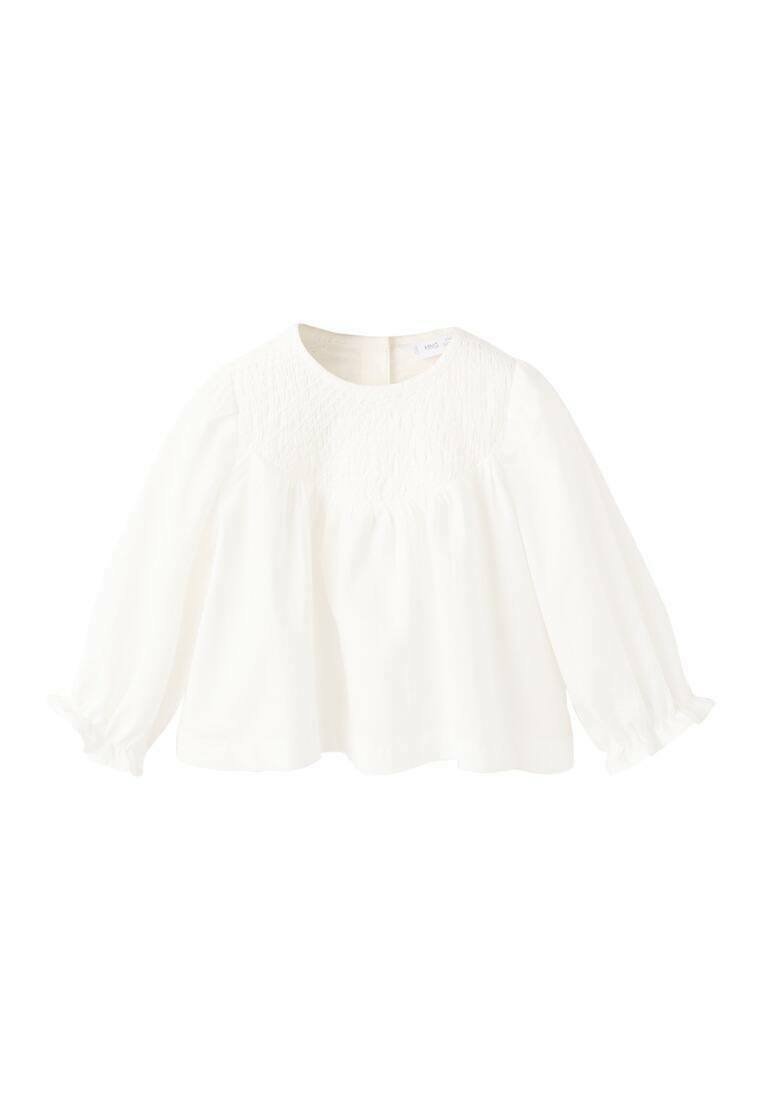 Bela dolgoročna bluza z okroglim izrezom, okrašena s smokom na sprednjem delu in nabranimi rokavi, ki se zaključujejo z elastičnimi manšetami.