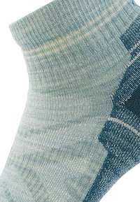 Helleblaue Baumwollsocke mit einem gerippten Bund, der auf der Seite ein dunkleres blaues strukturiertes Muster und subtile grünliche Streifen aufweist.