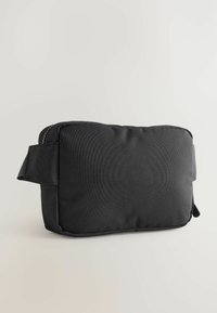 Black rectangular fabric bag with a zip closure and a side strap. Features a textured surface and a streamlined design.