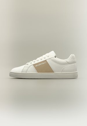 Baskets basses blanches avec panneau beige et logo Valentino blanc sur le côté, fermeture à lacets à l’avant, semelle en caoutchouc plate.