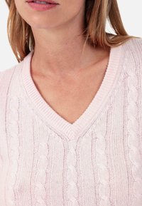 Hellrosa Strickpullover mit Zopfmuster, V-Ausschnitt und strukturiertem Muster, mit gerippten Details am Ausschnitt und an den Schultern.