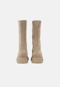Beige suede knee-high boots with a textured finish, flat rubber soles, and vertical seams along the sides, featuring a rounded toe design.