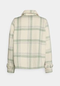 Károvaná bunda s světle béžovým základem a zelenými a šedými pruhy, vyrobená z měkké látky, s límečkem a ohrnutými manžetami.