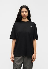 Μαύρο φαρδύ T-shirt από βαμβάκι, με στρογγυλή λαιμόκοψη και κοντά μανίκια. Μικρό λευκό λογότυπο στο αριστερό στήθος.