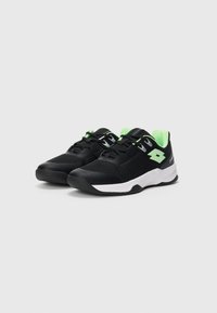 Ein Paar schwarze Sport Schuhe mit grünen Akzenten, weißen Sohlen und Mesh-Stoff, schräg dargestellt, um die Vorder- und Seitenansicht zu zeigen.