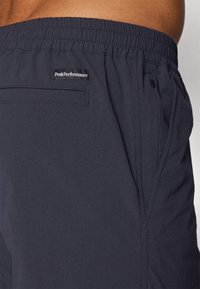Mørk marineblå shorts laget av strukturert stoff. Har elastisk midje, sidelommer og et logomerke på baklommen.
