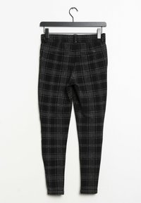 Pantalones de cuadros en negro y gris con un diseño ajustado, confeccionados en una tela texturizada, que cuentan con una cinturilla elástica y sin cierres visibles.