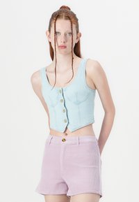 Világoskék farmer cropped top, gombos elülső résszel, amely világos rózsaszín kordbársony sorttal van párosítva. Formázott kialakítása és vastag pántjai jellemzik.