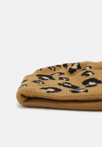 Pletená čiapka v béžovej farbe s čierno-krémovým leopardím vzorom. Mäkká textúra s prehnutým lemom na spodnej strane.