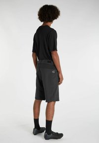 Schwarzes sportliches T-Shirt kombiniert mit dunkelgrauen Shorts, die mit einer Gesäßtasche und strukturierter Oberfläche ausgestattet sind. Das Modell steht mit dem Rücken zur Kamera.