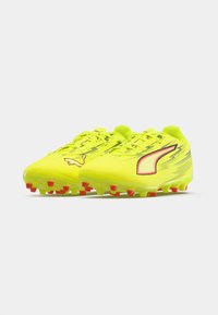 Neon yellow football cleats with red accents, textured synthetic upper, lightweight design, featuring traditional laces and molded studs.